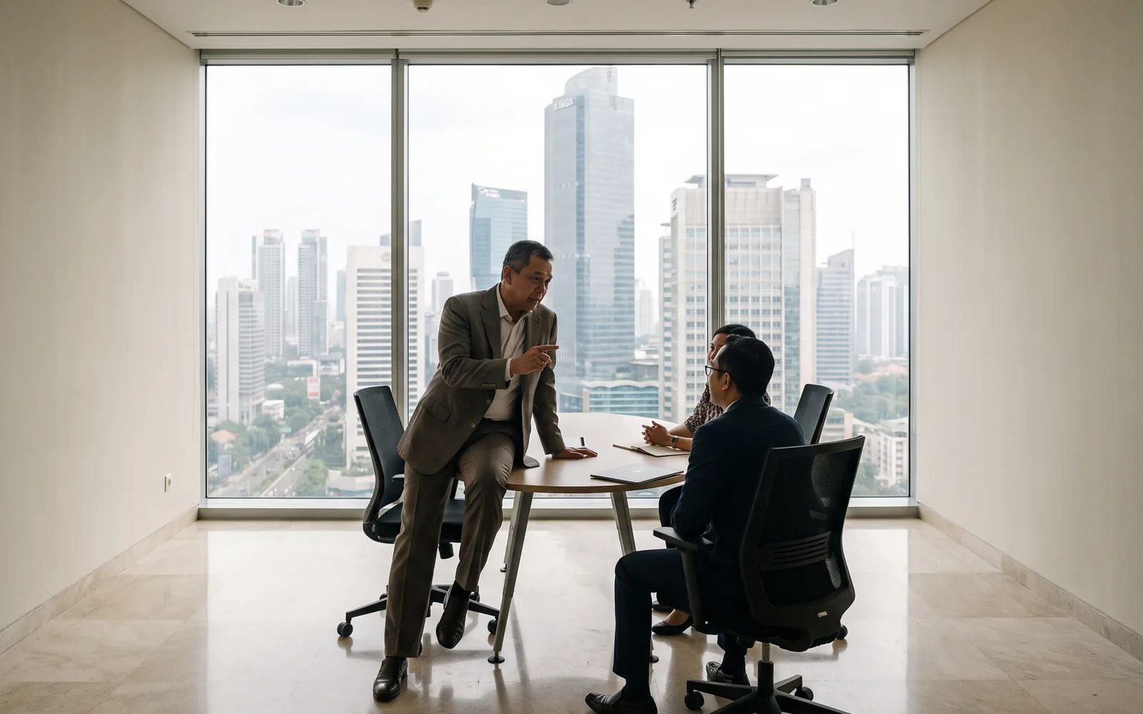 A senior executive in a calm, light-filled Jakarta office, the business district beyond the glass